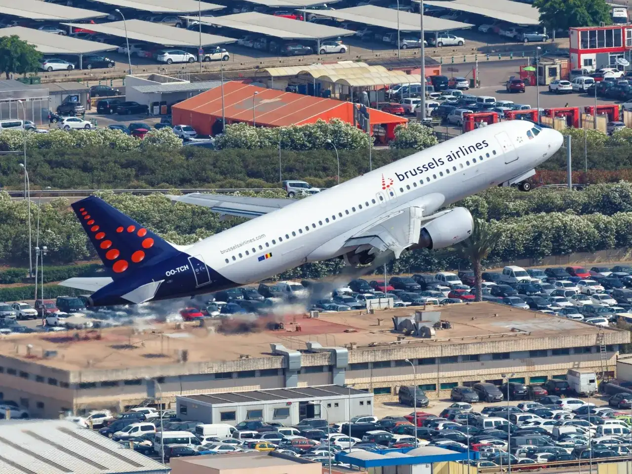 Samolot Brussels Airlines startuje z lotniska Bruksela Charleroi, unosząc się nad zatłoczonym parkingiem.