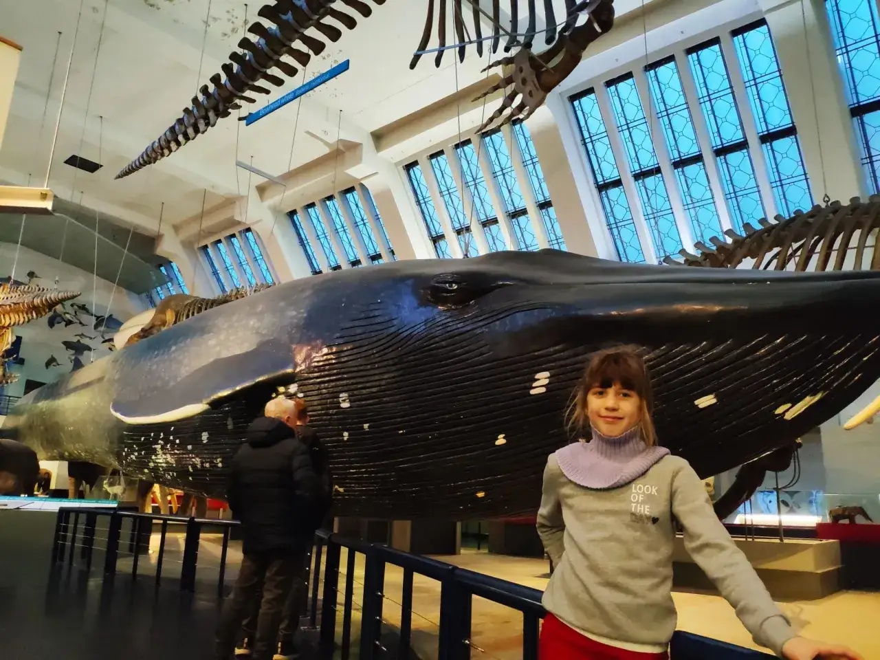 Dziewczynka pozuje przed gigantycznym modelem płetwala błękitnego w Muzeum Historii Naturalnej w Londynie.