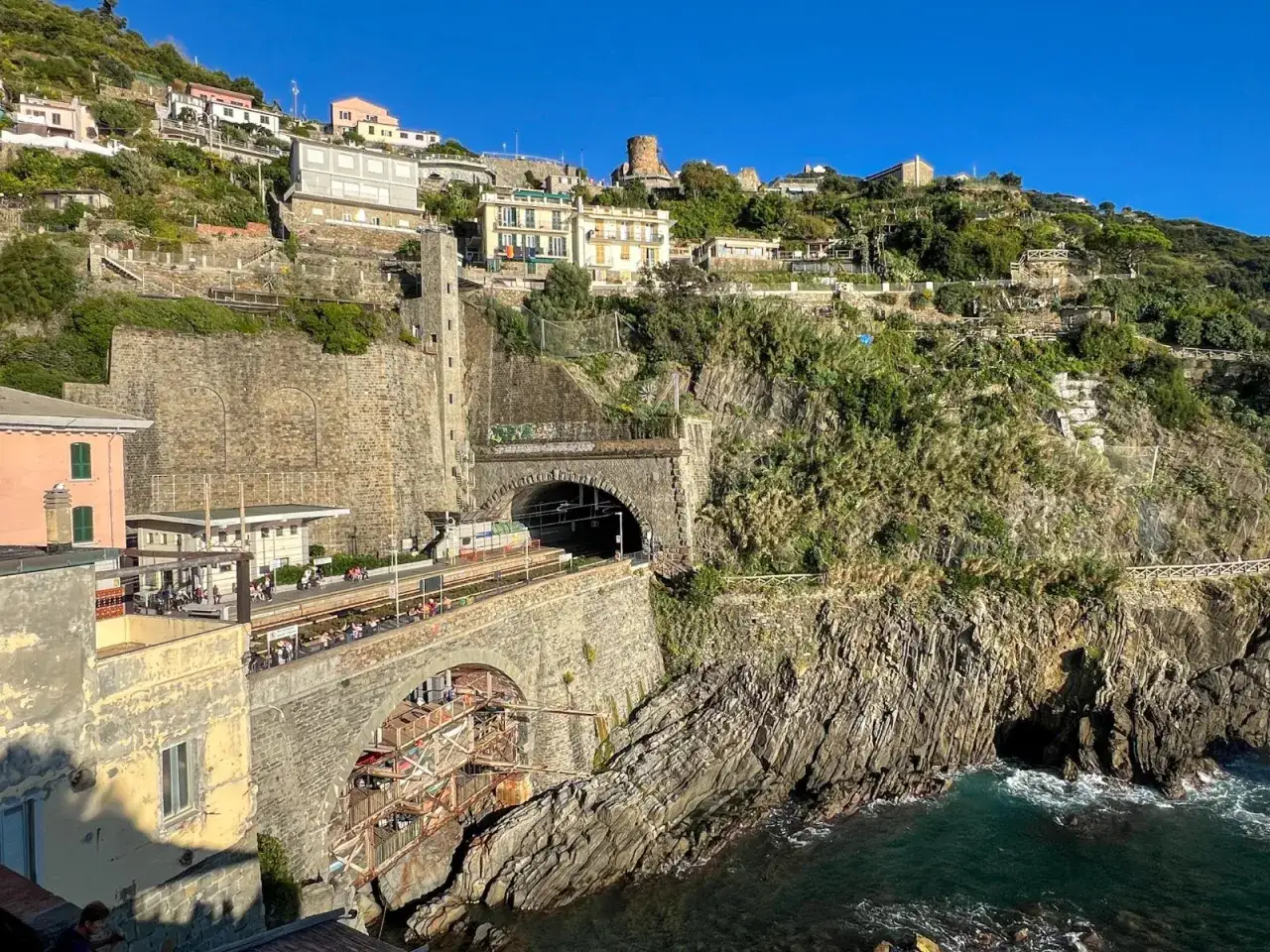 Widok na klifowe wybrzeże Cinque Terre, prowincja La Spezia, Włochy. Pociąg wjeżdża do tunelu wykutego w skale.
