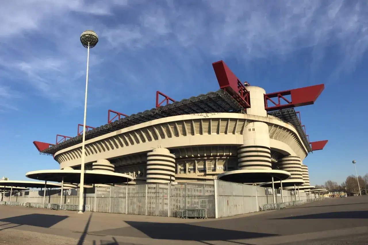 Stadion Interu Mediolan z charakterystycznymi czerwonymi elementami dachu i okrągłymi wieżami.