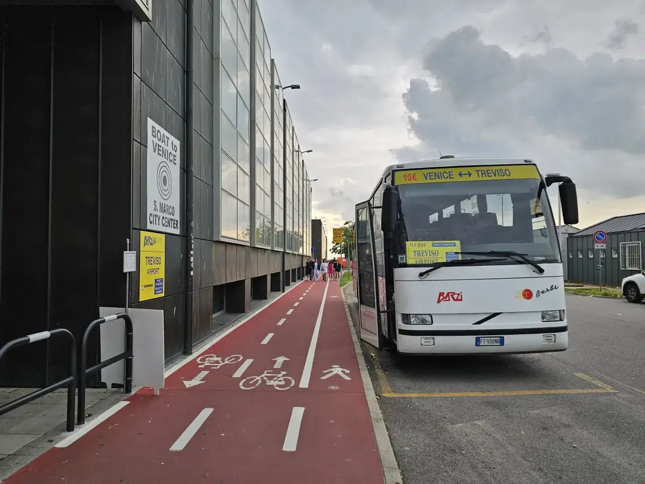 Autobus na lotnisku Treviso, gotowy do odjazdu do Wenecji. Czerwona ścieżka rowerowa i chodnik obok budynku.