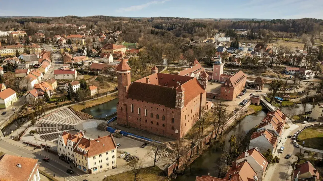 Zamek w Lidzbarku Warmińskim, jedna z głównych atrakcji miasta, otoczony wodą i urokliwą zabudową.