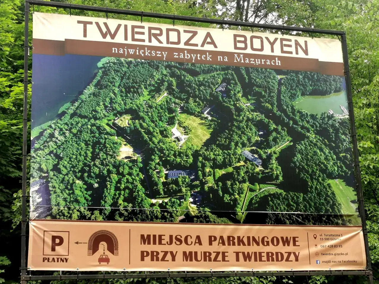 Widok z lotu ptaka na Twierdzę Boyen w Giżycku, największy zabytek na Mazurach. Pod spodem informacja o płatnym parkingu przy murach twierdzy.